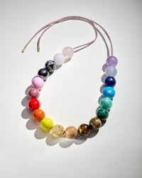 Soho gold necklace including amethyst, chalcedony, lapis lazuli, amazonite, malachite, unakite, tiger's eye, rhodonite, rose quartz, white agate, snowflake obsidian and hematite semi precious stones, sky, camel, lemon, terracotta, big apple red and flamingo coloured enamel spheres with an 18k yellow gold florentine frosted finish sphere