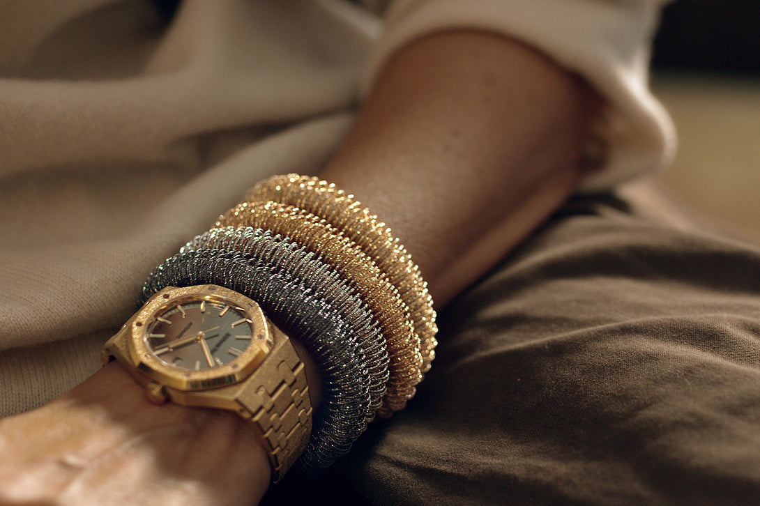 Carolina Bucci wearing a stack of four K.I.S.S. bracelets in 18k gold, paired with Audemards Piguet's Royal Oak watch in our signature Florentine Finish.