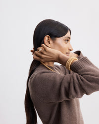 side profile of 18k yellow gold kiss necklace modelled with 18k yellow gold kiss necklace with 18k yellow, white and rose gold florentine frosted finish thick rings