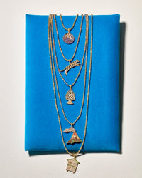 18k Yellow Gold blueberry, jaguar, good luck pinecone, volcano and cabina pendant connected to separate disco ball bracelets, presented on blue velvet mattress