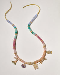 Memory pendant including forte beads, 20 18k yellow gold beads and 18k yellow gold leopard, good-luck pinecone, volcano, blueberry, cabina and on white background