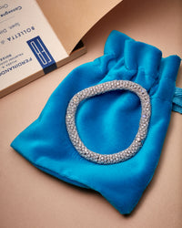 18k white gold Twister Luxe bracelet encased in pavé white diamonds placed on blue velvet pouch.