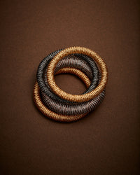 18k yellow, white, rose and black gold kiss bracelet on oak background