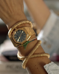 side profile of 18k yellow gold kiss necklace modelled around the wrist wrapped