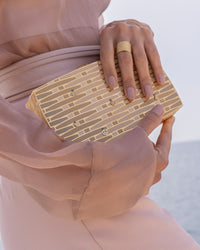 close up of 18k yellow florentine frosted finish gold woven wishes clutch bag with layered enamel with 18k florentine frosted finish cuff ring